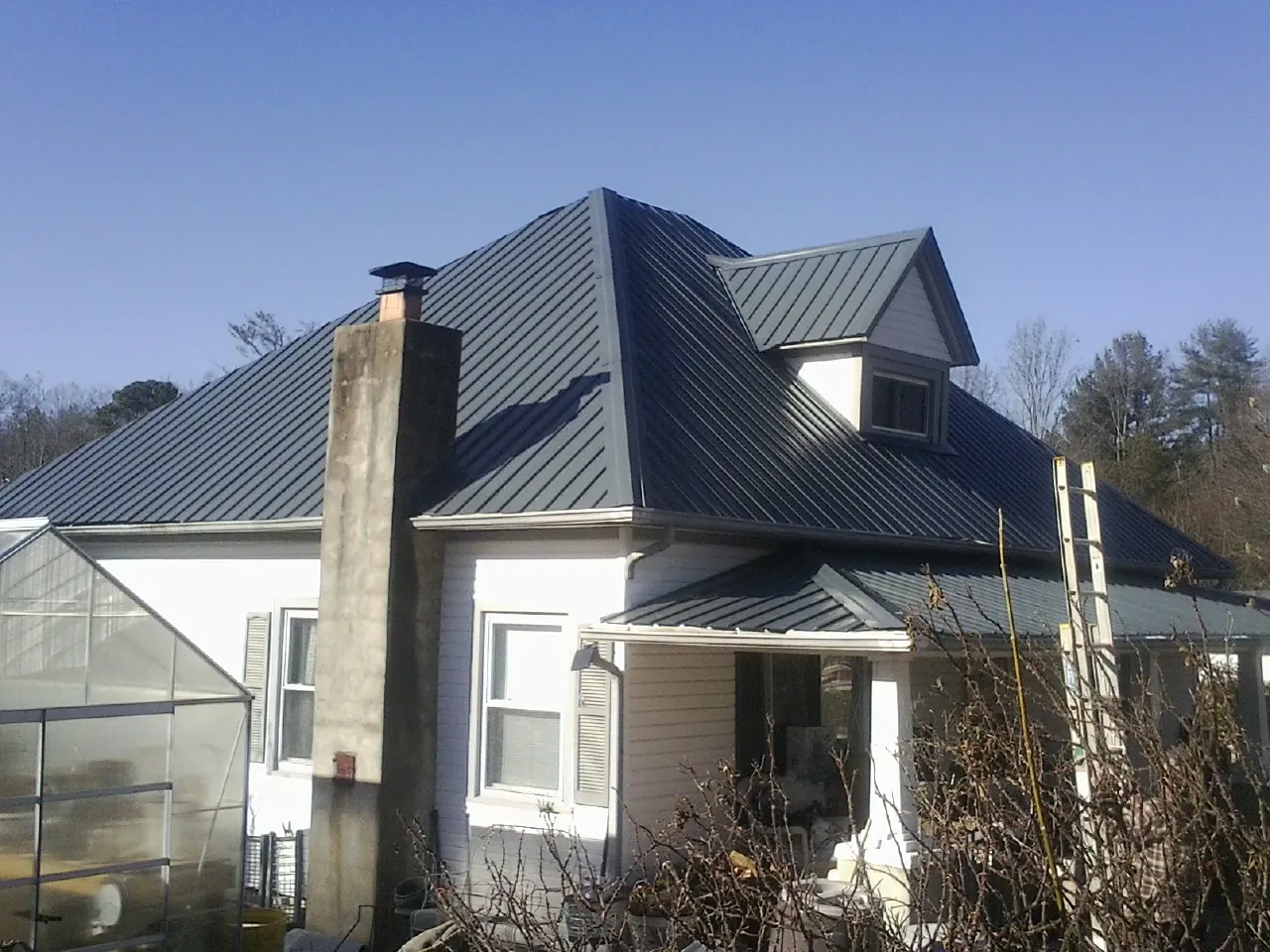 Dark blue standing seam metal roof on a white farmhouse with dormer — Slate & Tile Roof Repair by Roofing Brothers in Cross Anchor