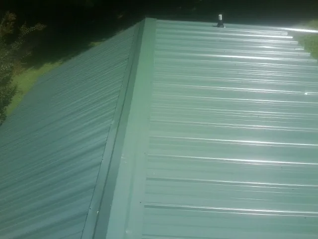 New green metal panels meeting at the ridge of a roof — Flat Roof Repair work by our crew in Cross Anchor