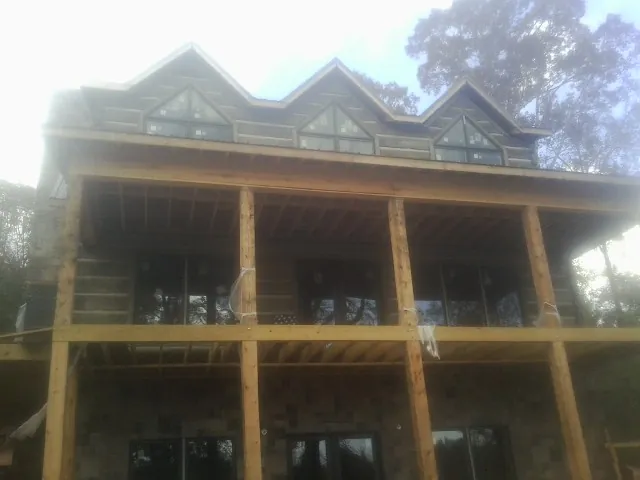 Dormers and porch framing on a large log home under construction — Roof Coating work by our crew in Cross Anchor
