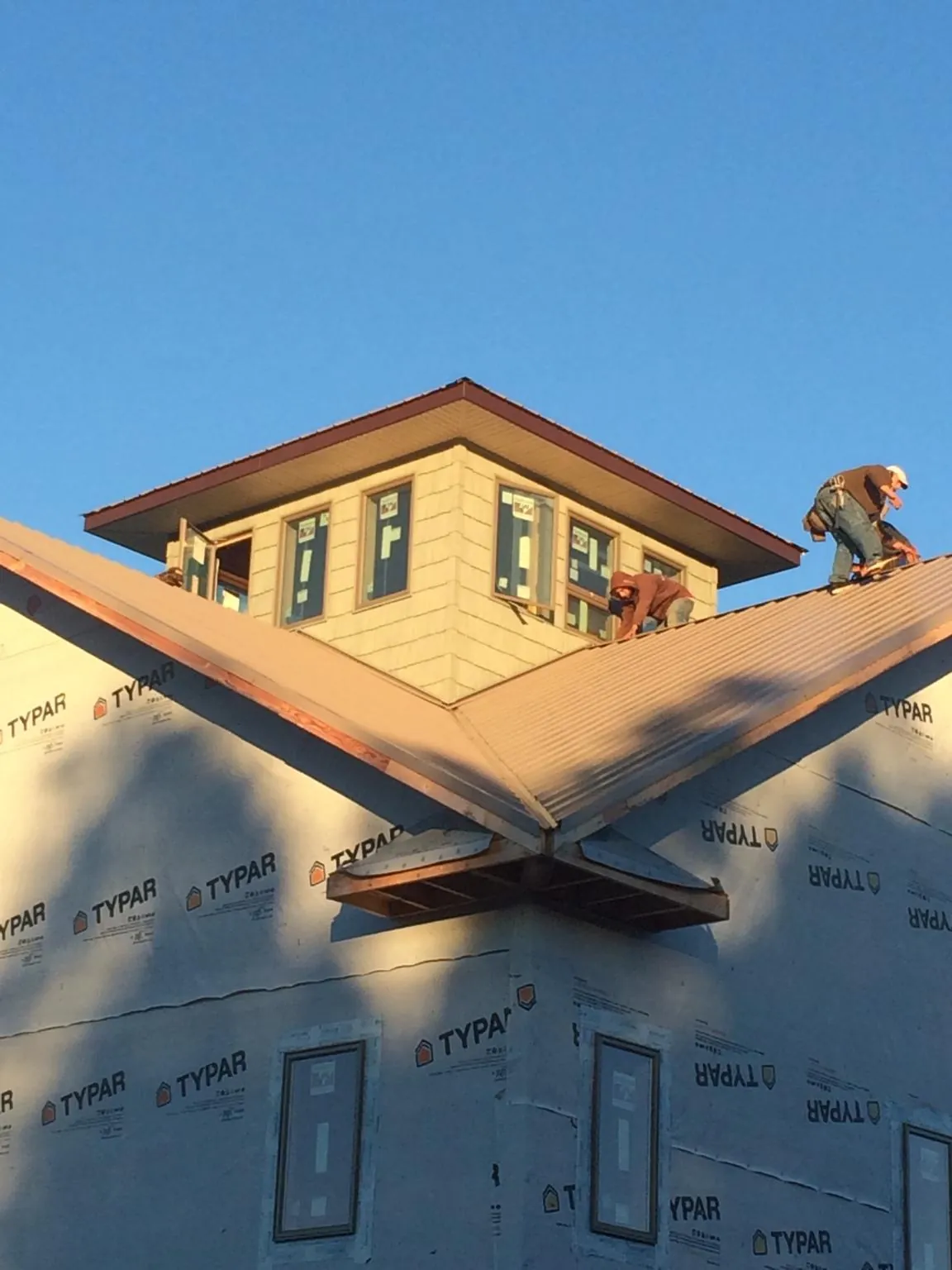Roofers working around a rooftop cupola on a new metal roof at sunset — Roof Waterproofing in Cross Anchor by Roofing Brothers